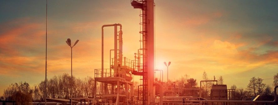 Industrial gas plant silhouetted against a warm sunset sky