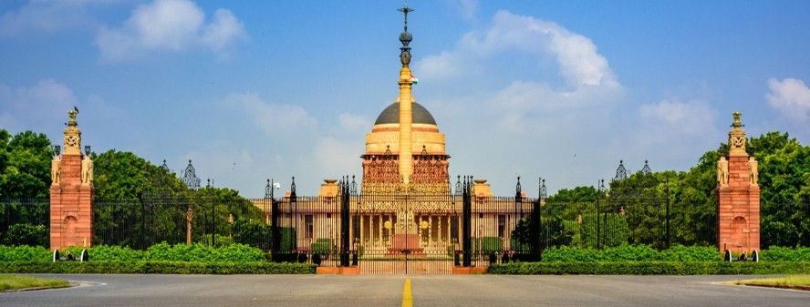 Rashtrapati Bhavan framed by green hedges under a clear blue sky
