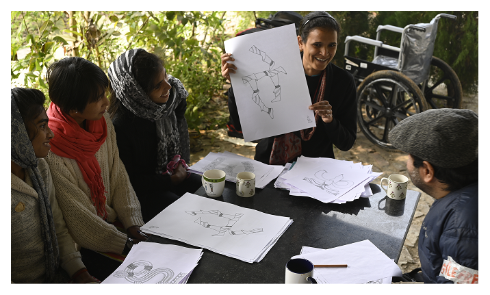 Teachers and learners reviewing Akshar Chitra drawings around an outdoor table