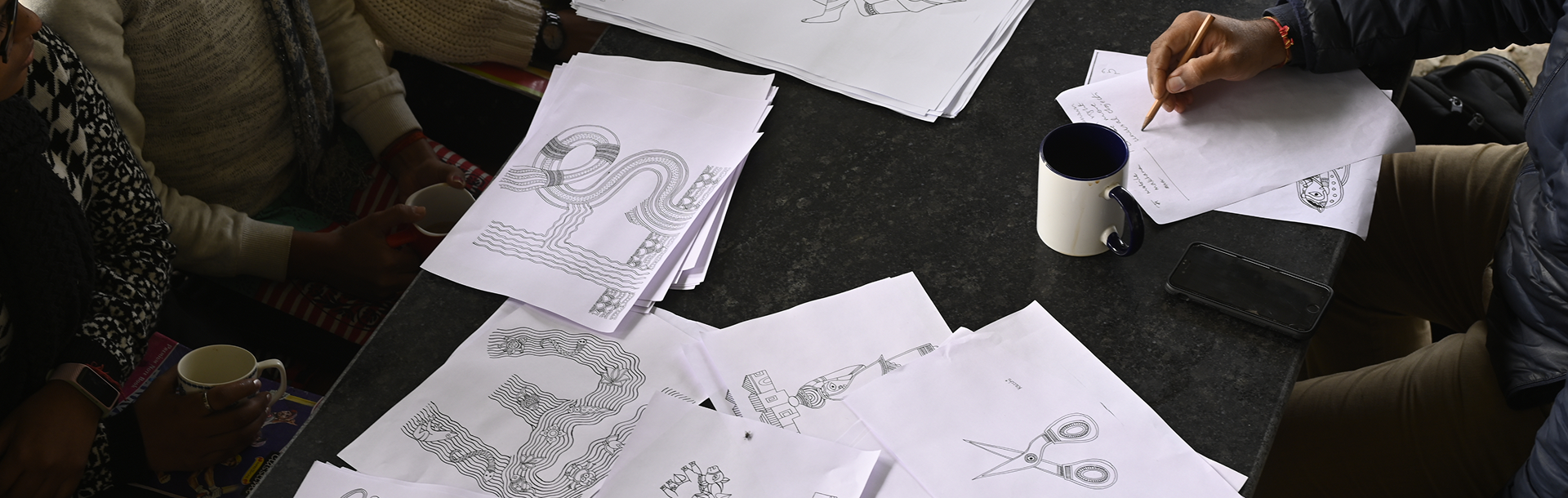 Workshop table covered with Akshar Chitra letterform drawings