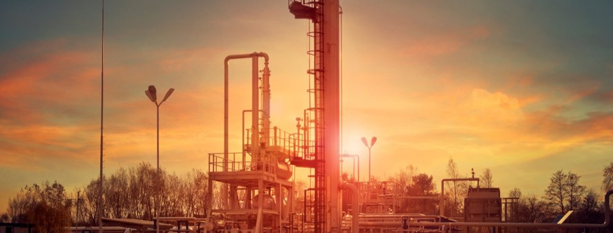 Industrial gas plant silhouetted against a warm sunset sky