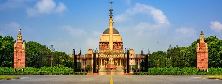 Rashtrapati Bhavan framed by green hedges under a clear blue sky